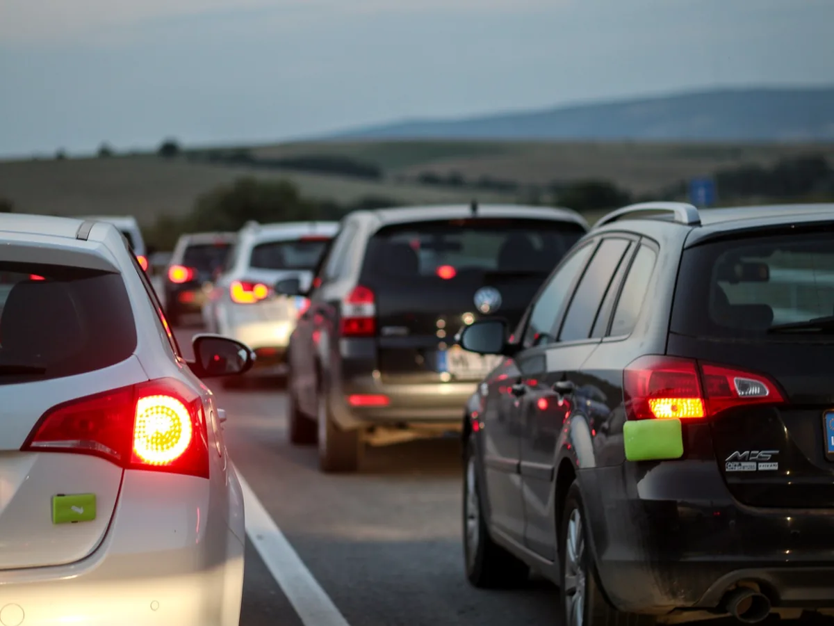 Zadnja svjetla i uključeni pokazivači automobila u koloni na prilazu graničnom prijelazu u sumrak